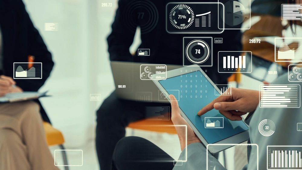 Profissionais analisando dados em um tablet e notebook, com gráficos digitais sobrepostos, representando gestão, monitoramento e segurança da informação na Alterdata.