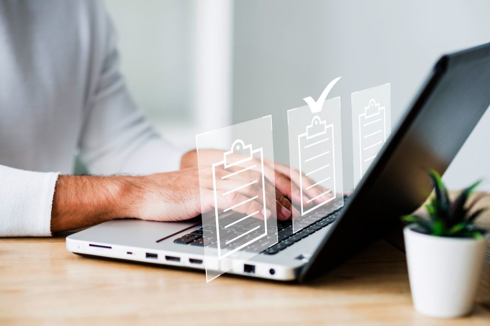 Pessoa digitando em um notebook com ícones de checklist sobrepostos, simbolizando conformidade, organização e processos seguros nos sistemas da Alterdata.